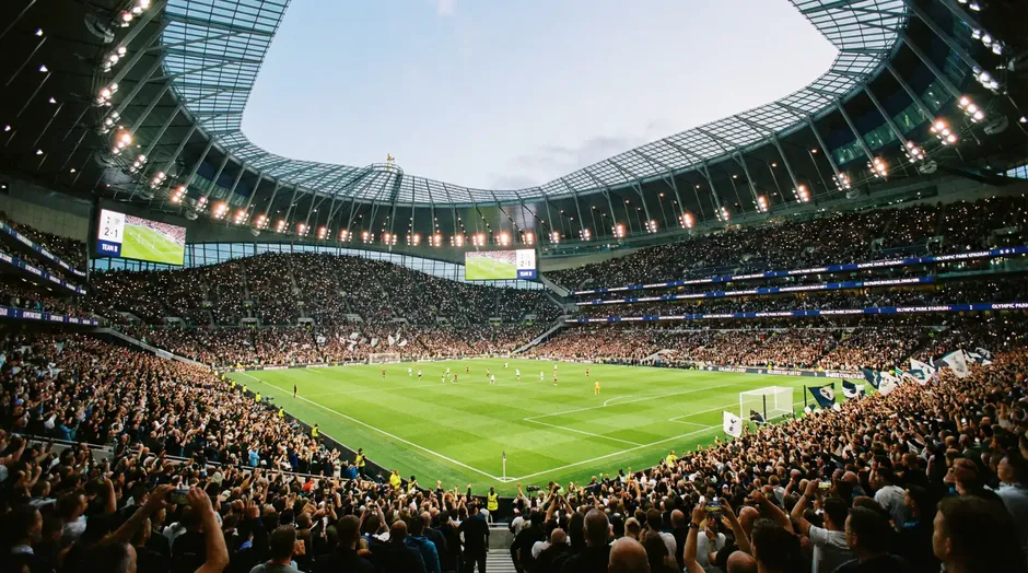 Moderný futbalový štadión s tribúnami plnými fanúšikov počas večerného zápasu
